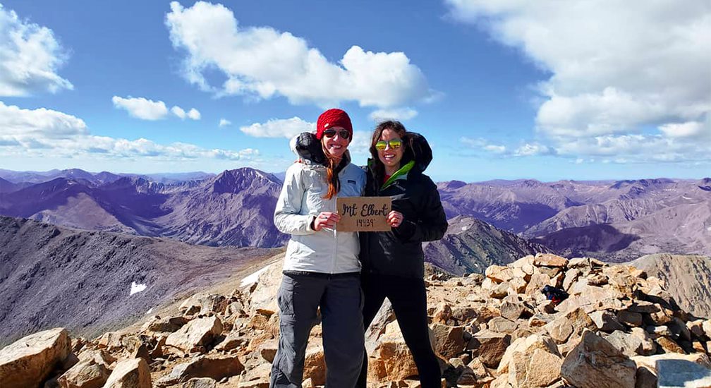 Two people summit a mountain